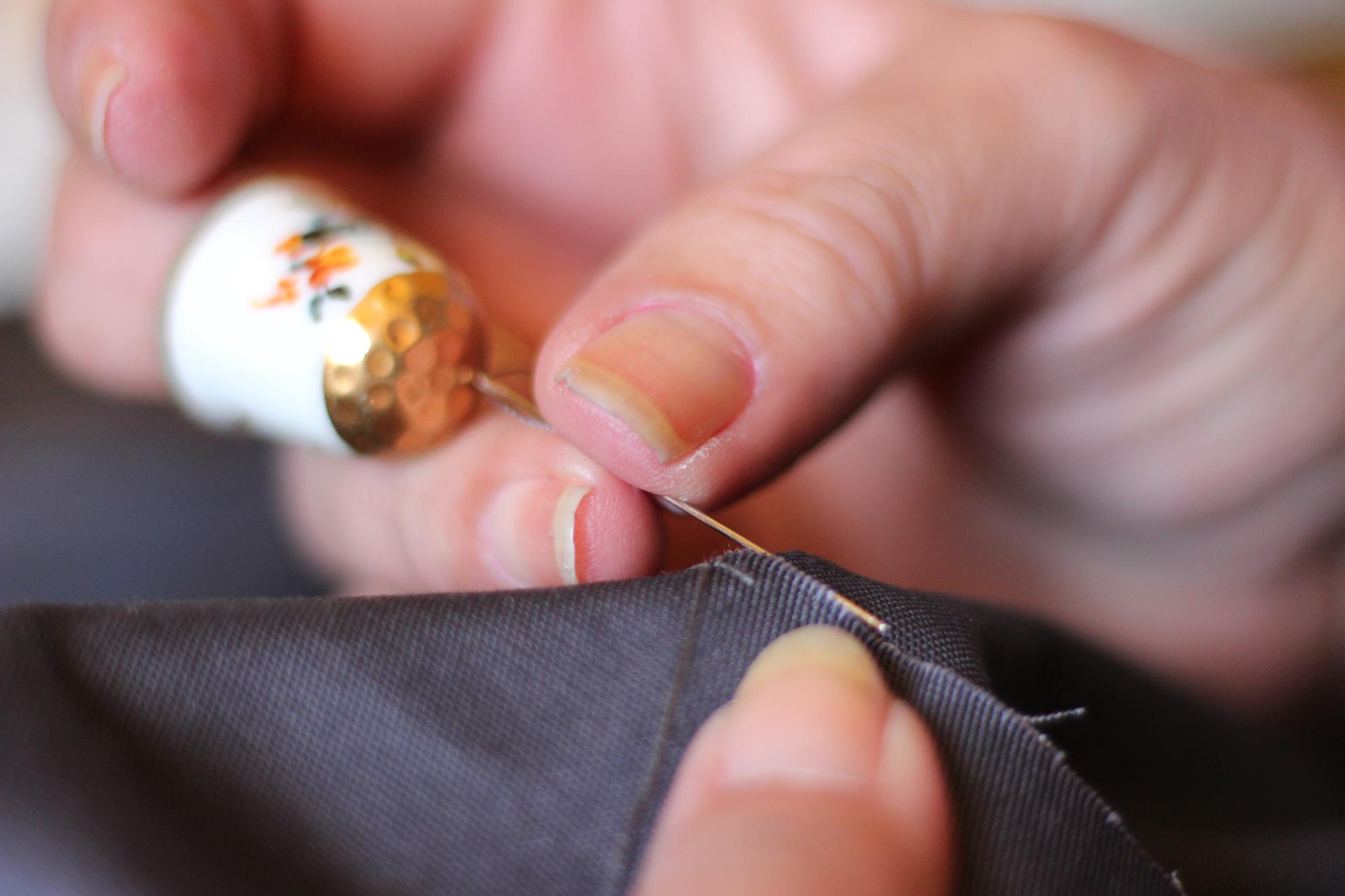 Artisan hands embroidering gold thread on silk